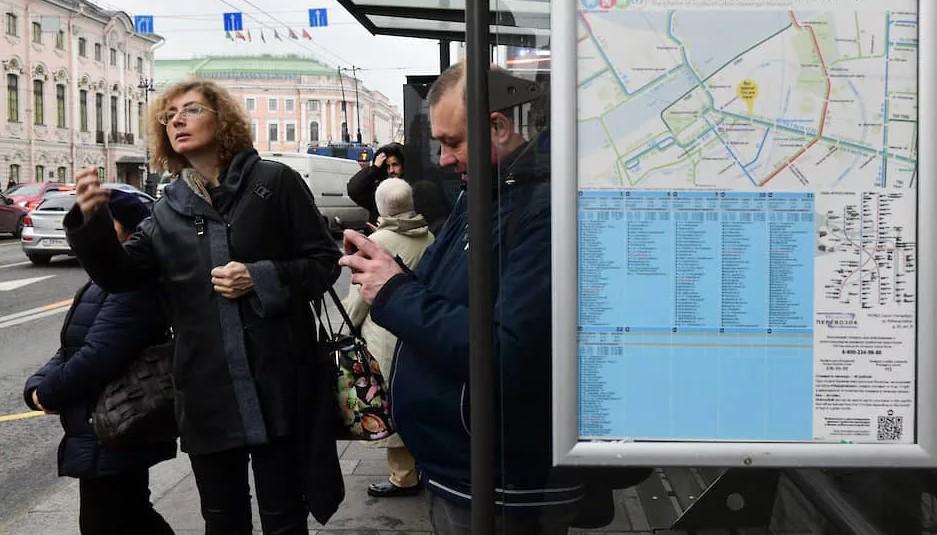 Фото жителей СПб на автобусной остановке с отзывами о транспортной реформе.