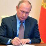 На фото президент РФ подписывает указ об индексации пенсий в РФ.