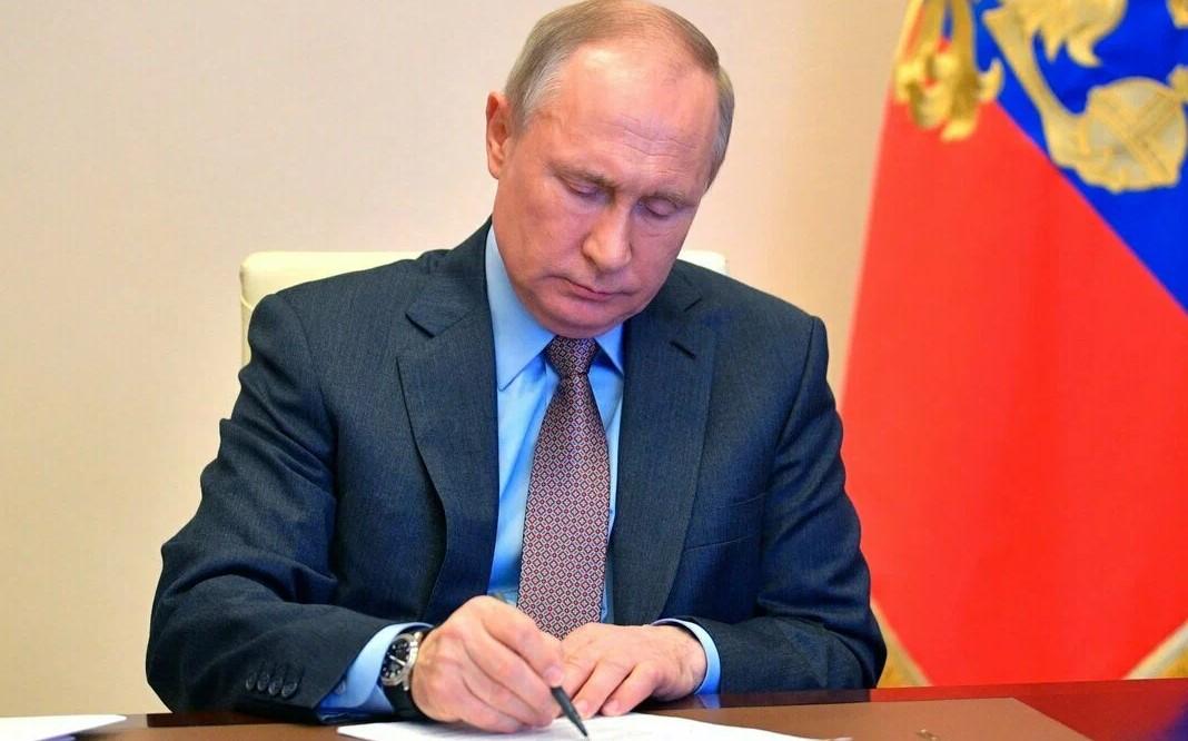 На фото президент РФ подписывает указ об индексации пенсий в РФ.