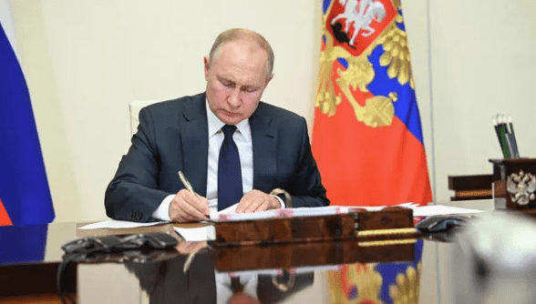 На фото Путин подписывает новый указ.
