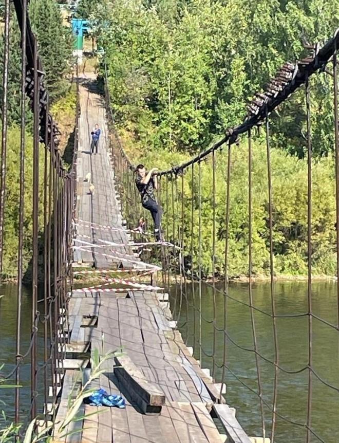Человек перебирается по мостовым тросам.
