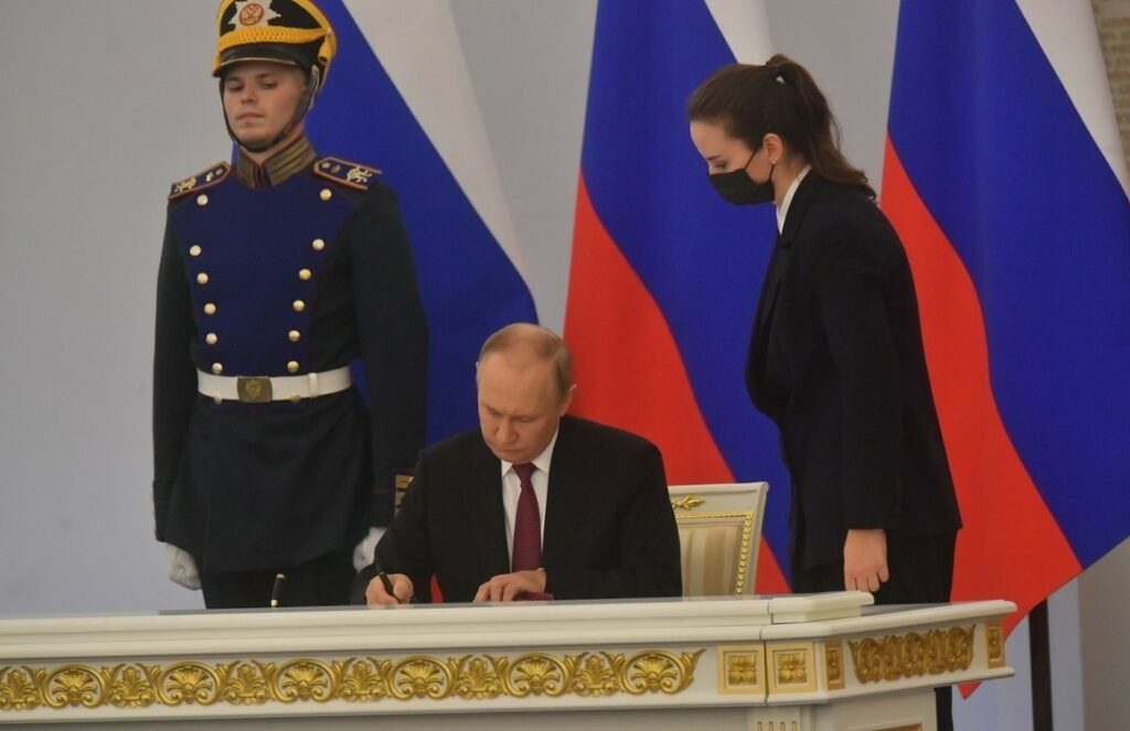 На фото Путин подписал документацию.