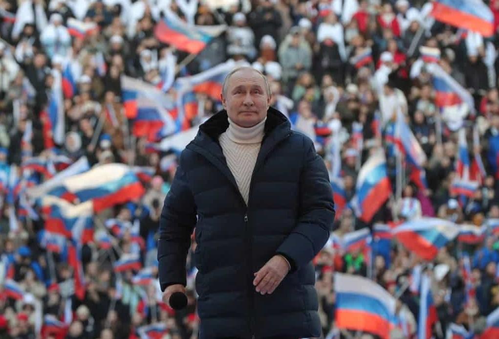 На фото Путин, а на фоне массы народа с российскими знамёнами.