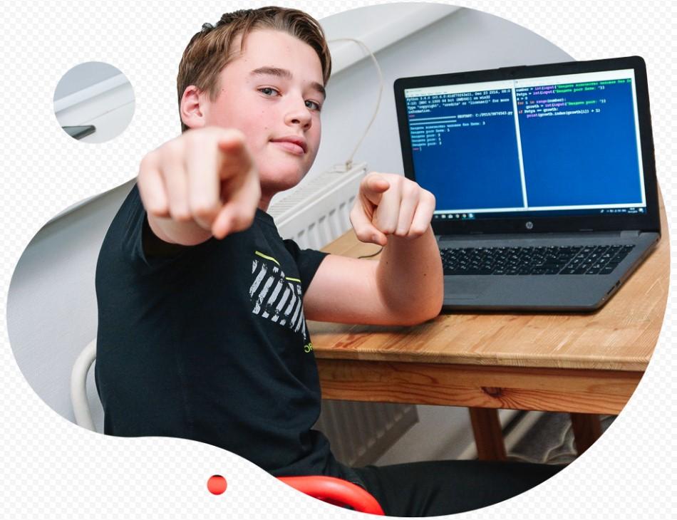 На фото подросток-мальчик сидит за компьютерной программой изучая программирование.